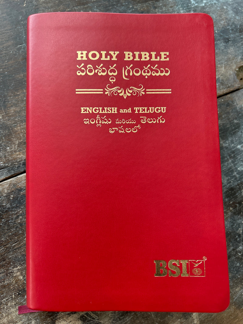 Red Bible with English and Telugu text on a wooden surface