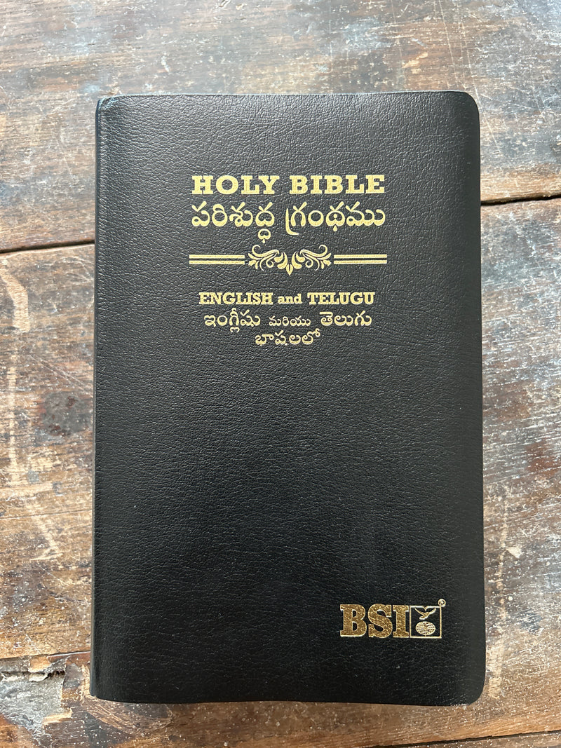 Black Bible with gold text on a wooden surface